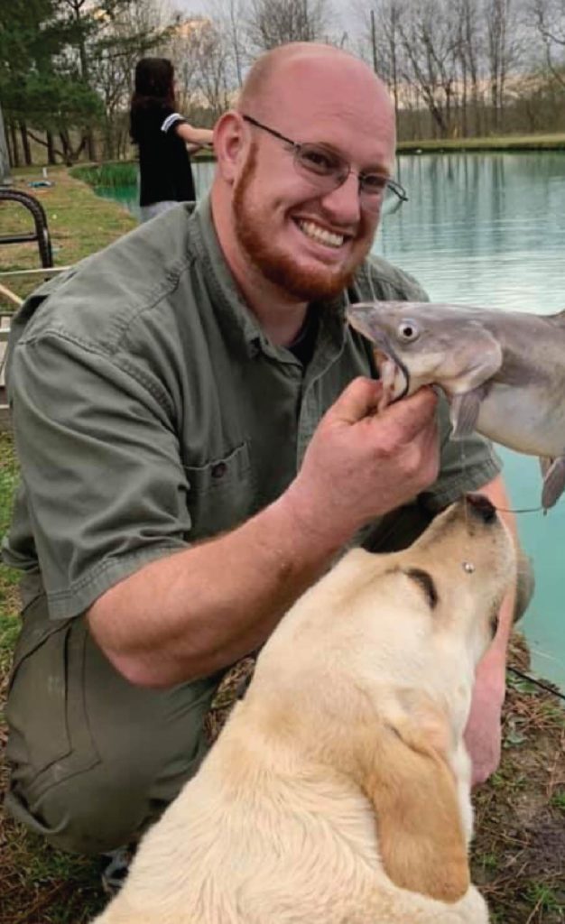 Board President Micah Seavers posing with a dog and a fish he caught